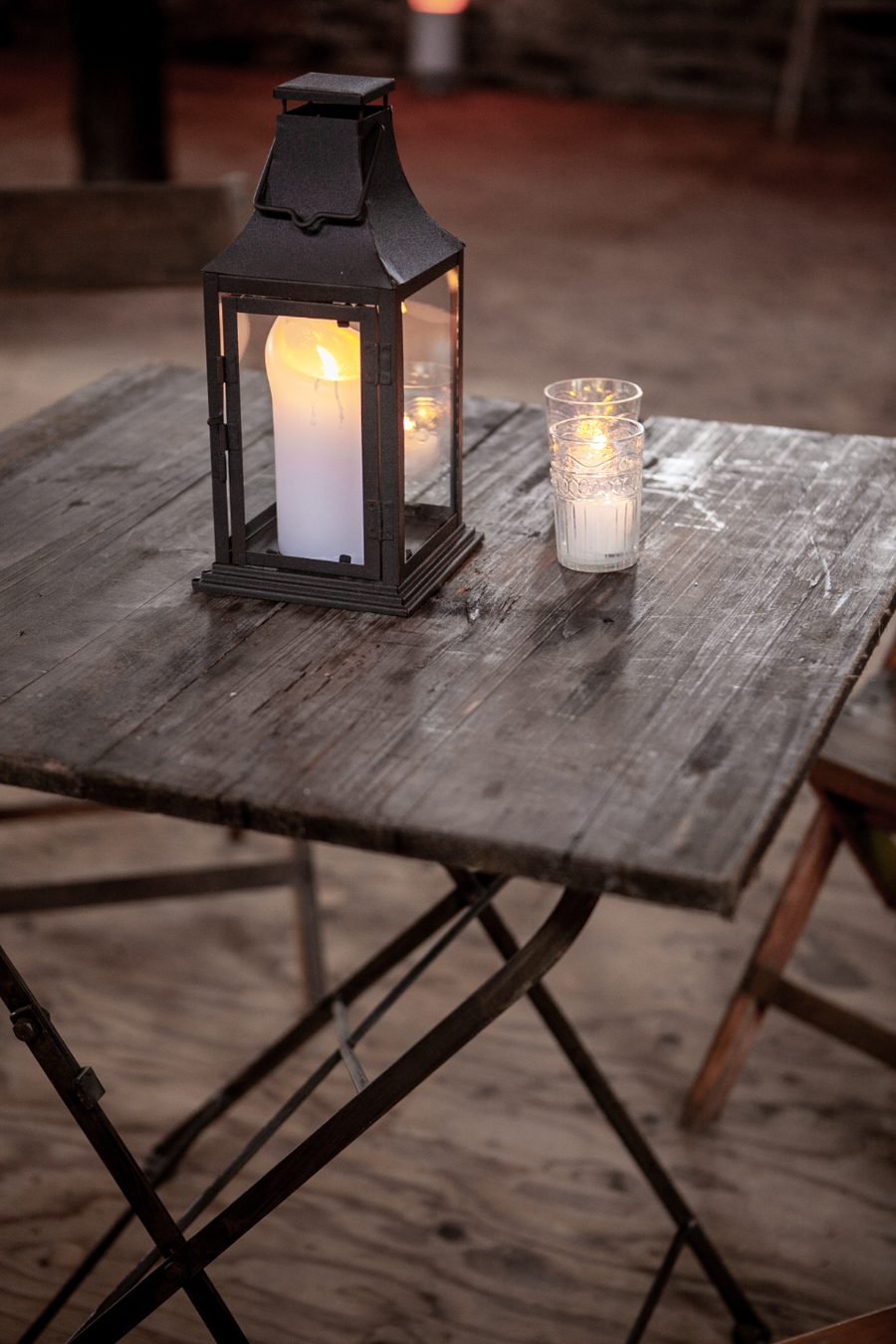 Une lanterne allumée sur une table de bois, le soir